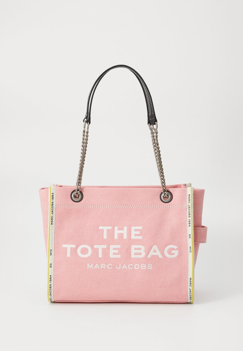 Pink canvas tote bag with silver chain handles, white "THE TOTE BAG MARC JACOBS" text, and branded white-yellow side trims.
