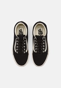 Czarne płócienne trampki mają białe akcenty, okrągły nosek i osiem par dziurek na sznurowadła. Podszewka jest w kolorze kremowym z markową wkładką.