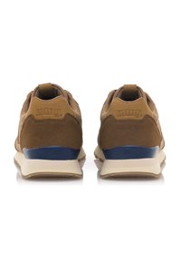 Zapatillas de ante y cuero marrones con suelas beige, que presentan un acento azul marino en el talón y el logo. La vista trasera resalta las texturas contrastantes.