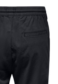 Schwarze Sporthosen mit einem elastischen Bund und einer einzelnen Gesäßtasche mit Klappe. Der Stoff hat eine glatte, matte Textur.