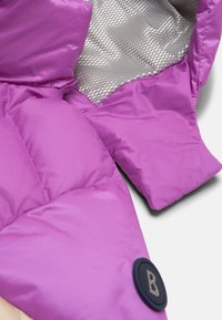 Purple puffer jacket section featuring a smooth exterior and a silver, textured lining. Also includes a circular logo with a 'B' emblem.