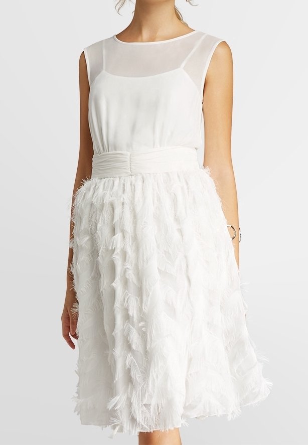 Robe blanche dotée d'un corsage ajusté avec superposition transparente et d'une jupe évasée ornée de détails texturés ressemblant à des plumes.