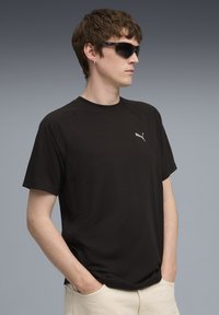 Sort kortærmet T-shirt med rund halsudskærning og et lille hvidt Puma-logo på brystet. Glat stof, afslappet pasform.