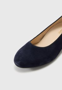 Shoe flat em camurça azul-marinho com biqueira redonda e um design minimalista. Textura suave e um fino acabamento preto à volta da abertura.