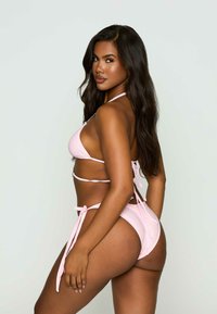 Roze bikini set met halternek en verstelbare bandjes. Beschikt over een gladde textuur, minimale bedekking en een klassiek triangel topontwerp.