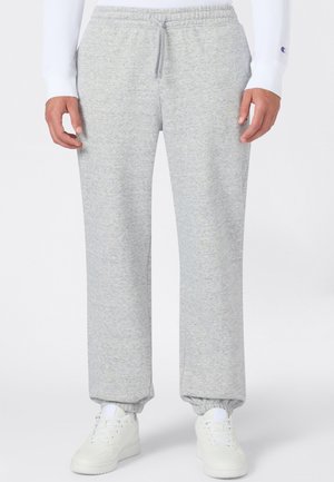 Hellgraue Sweatpants mit elastischem Bund und Bündchen, getragen mit weißen Sneakers und einem weißen Langarmshirt.