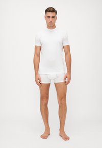 Weißes T-Shirt mit kurzen Ärmeln und weiße Unterwäsche, aus glattem Stoff gefertigt, körpernahe Passform, zeigt klare Linien und minimales Branding.