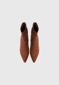 Stivaletti alla caviglia in suede marrone con punta affusolata, caratterizzati da una texture liscia e dettagli in zip argentata sul lato esterno.