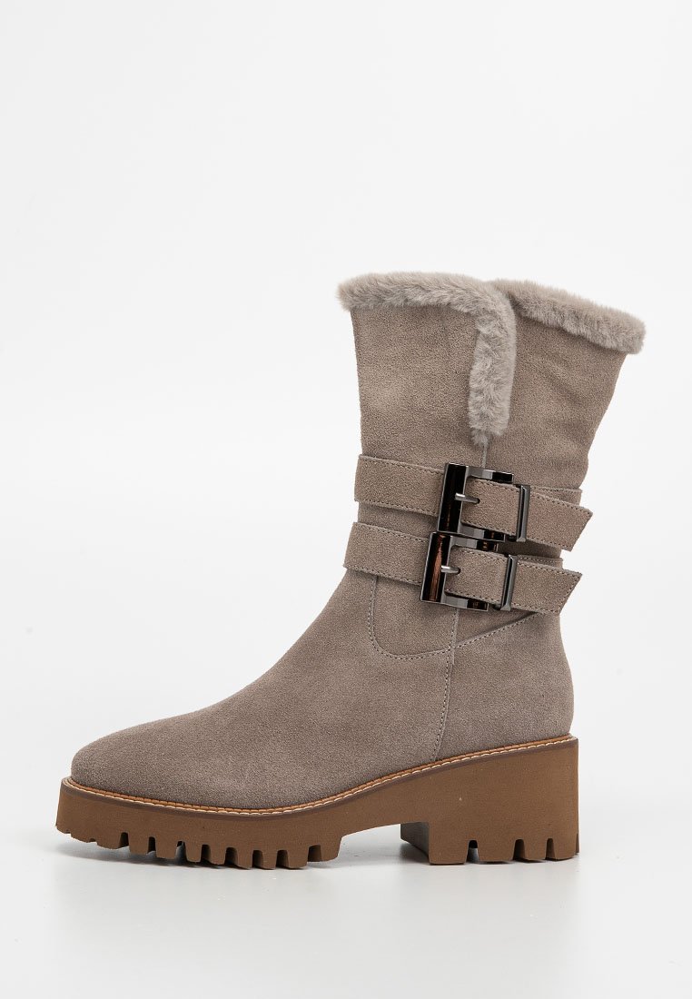 Botas de tobillo de ante topo con cuello de piel sintética, dos hebillas decorativas y una suela gruesa marrón con un borde serrado.