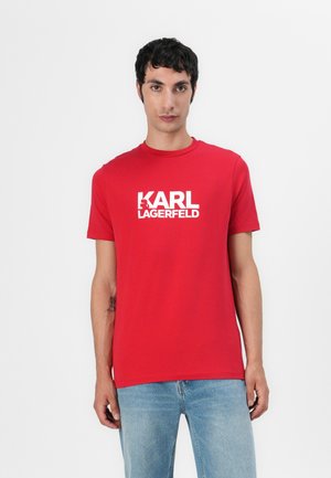 Raudona medvilninė marškinė su trumpomis rankovėmis ir apvaliu kaklu, su ryškiu baltu "KARL LAGERFELD" logotipo atvaizdu priekyje.