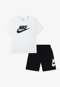 Λευκό βαμβακερό T-shirt με μαύρο λογότυπο Nike, συνδυασμένο με μαύρο σορτς που φέρει λευκό λογότυπο Nike. Και τα δύο είδη είναι καθημερινά και σχεδιασμένα για άνεση.