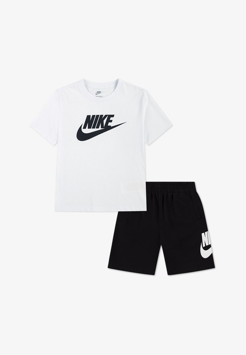 Camiseta blanca de algodón con un logo negro de Nike, combinada con pantalones cortos negros que llevan un logo blanco de Nike. Ambas prendas son informales y están diseñadas para la comodidad.