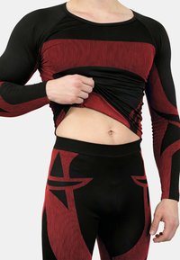 Long-sleeve athletic top and leggings in black and red with striped patterns. Soft material; fitted design accentuates body shape.