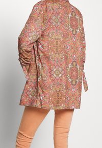 Chemise à manches longues à motif cachemire multicolore, en tissu à texture lisse, avec un ourlet arrondi et des liens aux poignets.