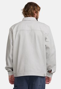 Light gray denim jacket featuring a classic collar, loose fit, and buttons at the cuffs. Simple design with a clean, smooth texture.
