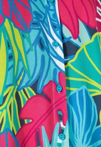 Napapaitakupa shirt yang menampilkan pola floral yang cerah dengan daun berwarna pink, hijau, dan biru. Terbuat dari kain ringan dengan kancing berwarna turquoise.