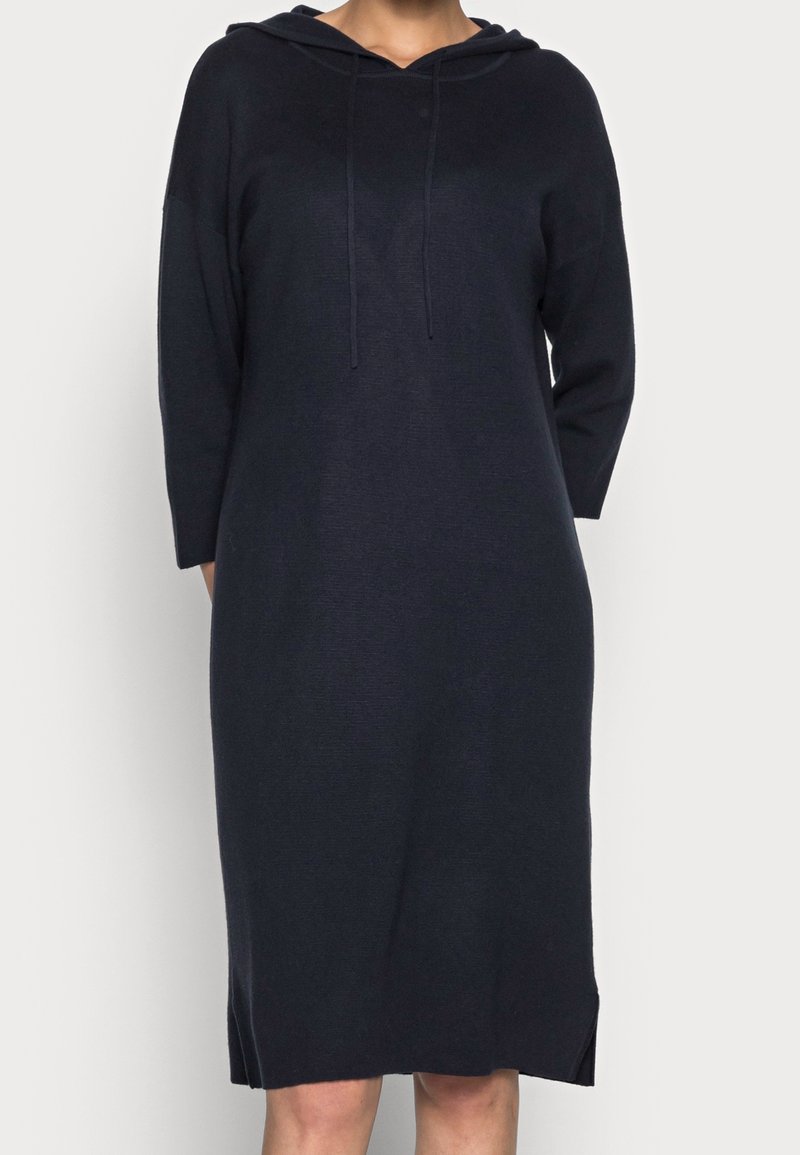 Huvtröjdress i mörk marinblå, tillverkad av ett mjukt stickat tyg. Har långa ärmar, en avslappnad passform och sprund i nederkanten.