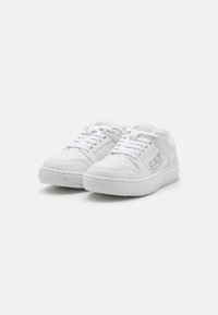 Hvite sneakers med en glatt læroverdel, perforert tå og teksturert gummisåle. Utsmykket med subtil merkevare på sidene.