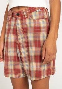 Červené, žluté a modré kárované šortky z lehké tkaniny. Mají zapínání na knoflík a boční kapsy, s volnějším střihem.