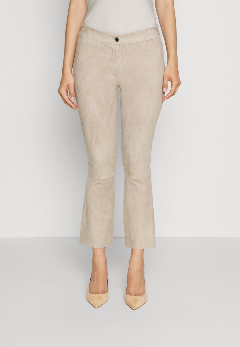 Beige suède broek met een getailleerde taille, een lichte flare aan de zoom en een enkele knoopsluiting aan de voorkant. Soepele textuur, geen zichtbare patronen.