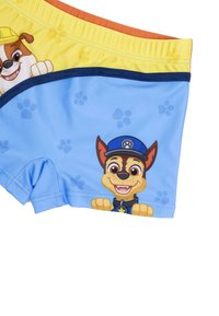 Shorts da bagno per bambini di colore blu con un cane dei cartoni animati. Il materiale è liscio ed elasticizzato, con dettagli in giallo e arancione sulla vita a contrasto.