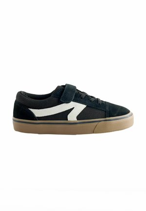 Black suede sneaker featuring a white zigzag design, lace and Velcro strap closure, and a textured gum rubber sole.