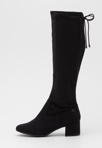 Botte noire montante en daim doux, avec un bout pointu, un talon bloc, et un panneau élastique sur le côté avec un nœud décoratif en haut.