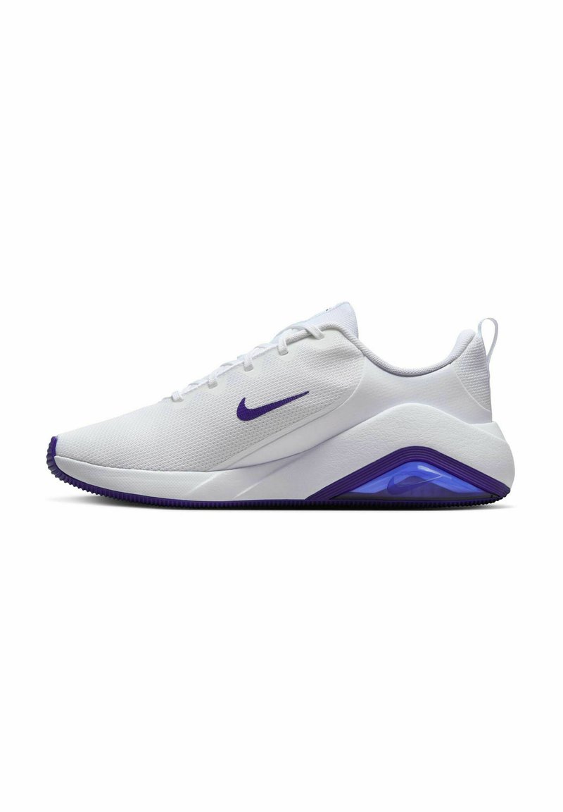 Zapatilla deportiva blanca con acentos morados y tela texturizada. Presenta una suela acolchada y una unidad de aire visible en el talón. Diseño ligero.