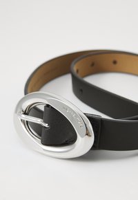 Black leather belt with a silver oval buckle, featuring a logo. The belt has a smooth texture and multiple adjustable holes for fitting.