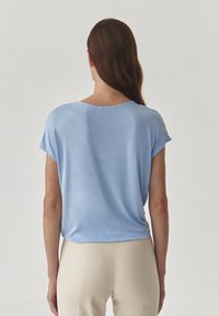 Top azzurro chiaro a maniche corte con vestibilità rilassata e scollatura rotonda, realizzato in tessuto morbido. Texture liscia con cuciture minime.
