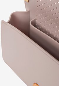 Lichtbeige handtas interieur met twee compartimenten, gestructureerd ontwerp, gladde textuur en stippenpatroon in het binnenste gedeelte. Gouden hardware accenten.