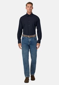 Camicetta blu a maniche lunghe con bottoni, jeans in denim blu, cintura intrecciata marrone, scarpe marroni; design pulito e aderente con texture e colori standard.