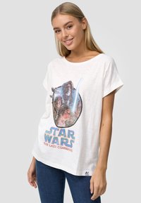 T-shirt bianco a maniche corte con grafica "Star Wars" che presenta personaggi e spade laser. Tessuto morbido, vestibilità rilassata e scollatura rotonda.