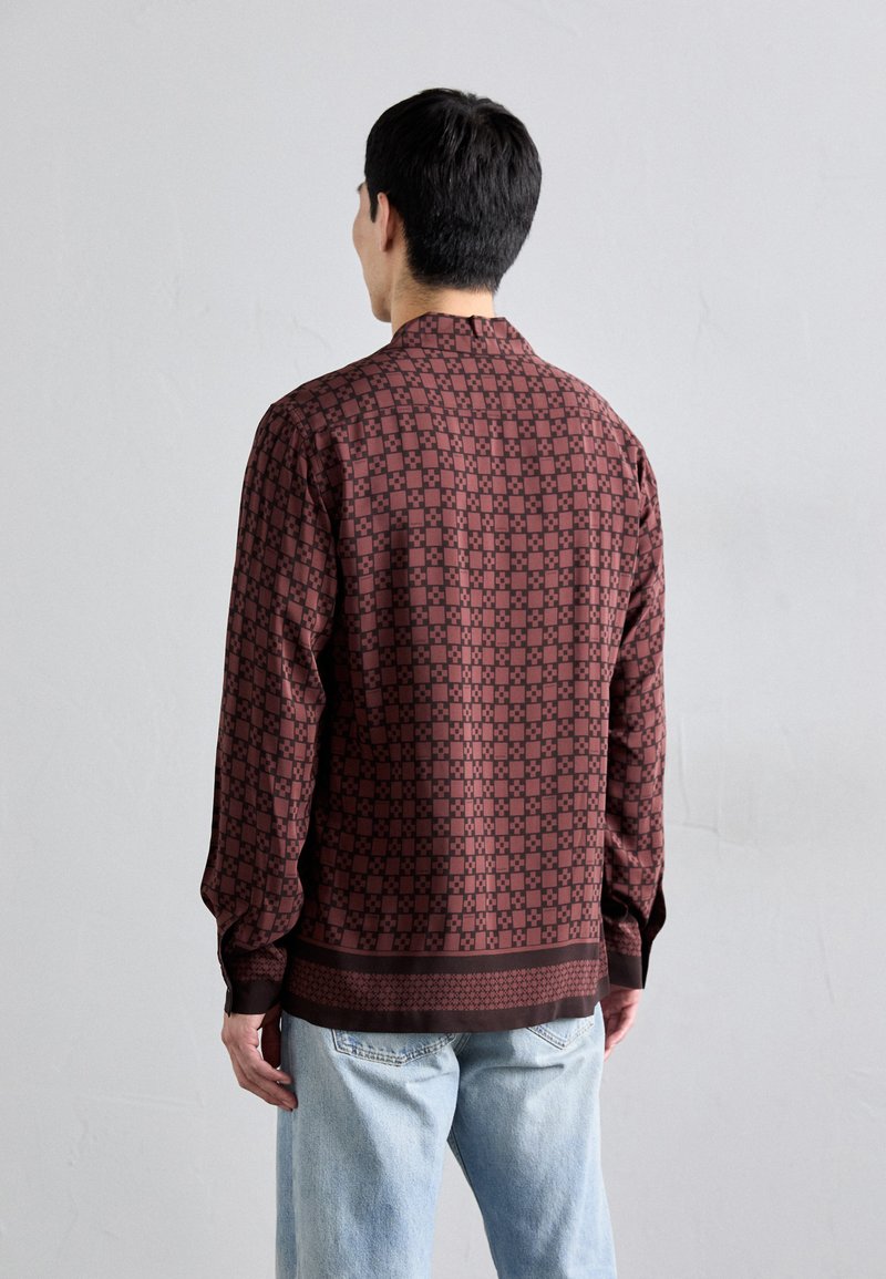 Camicia a maniche lunghe color bordeaux con motivo geometrico, polsini abbottonati e orlo dritto. Realizzata in tessuto morbido per una sensazione leggera.