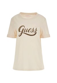 Camiseta de manga corta de color beige claro, hecha de algodón, con un logo brillante de color marrón de "Guess" y puños enrollados. Ajuste simple y relajado con cuello redondo.
