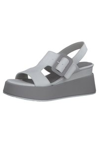Wedge-Sandalen aus weißem Leder mit ausgeschnittenem Design und einer großen grauen Schnalle. Sie verfügen über eine dicke graue Plateausohle für Stabilität.