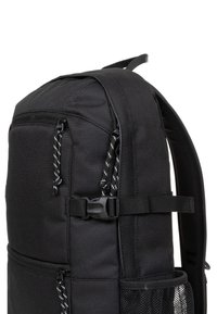 Mochila negra fabricada con un tejido duradero, que cuenta con un bolsillo de malla lateral, tirantes ajustables y un bolsillo frontal con cremallera de doble tirador.