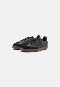 Black athletic shoes crafted from leather and suede, featuring three stripes, a gum rubber sole, and a rounded toe design.
