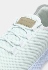 Jasnoniebieski siatkowy sneaker z teksturowaną cholewką, białymi sznurowadłami i brązową skórzaną metką z napisem "PIER-ONE". Posiada lekką, elastyczną podeszwę.