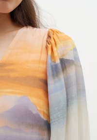 Chiffon obleka z v-izrezom; ima vzorec gorskega pokrajine v oranžnih, modrih in vijoličnih odtenkih; nežen material in nabran ramenski del.