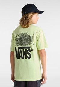 Světlounce zelené bavlněné tričko s černou grafikou pavučiny a logem "VANS" na zádech. Krátké rukávy a volný střih.