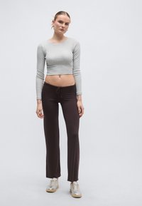 Hall hall varrukatega lühendatud topp ühendatud tumepruunide nööriga pükstega. Komplekti täiustavad paksu tallaga metallik-tossud.