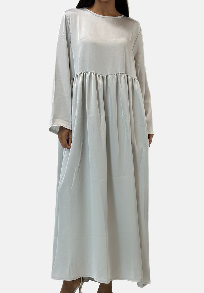 Robe gris clair à manches longues en tissu doux et brillant. Présente une taille froncée et une coupe fluide et ample.