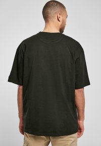 Black oversized t-shirt with short sleeves, round neck, made of cotton fabric, featured with a plain back design.