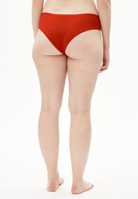 Bas de bikini rouge en tissu doux, présentant un design échancré et une taille élastique pour le confort. Pas de motifs ni d'accents visibles.