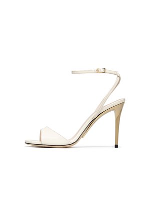 Beige high-heeled sandal with slim ankle strap and gold-tone buckle, open toe, and metallic stiletto heel.