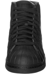 Svarta högtoppsneakers med texturerad läderöverkärl, gummiskalstopp och snörning. Har präglad logotyp och mönstrade detaljer.