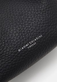 Black textured leather handbag featuring embossed brand name "GIANNI CHIARINI FIRENZE" in white. Rounded shape with a smooth finish.