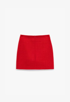 Rød tætsiddende mini nederdel med tekstureret stof, der har et subtilt ternet mønster og en centralt placeret lynlås bagpå.