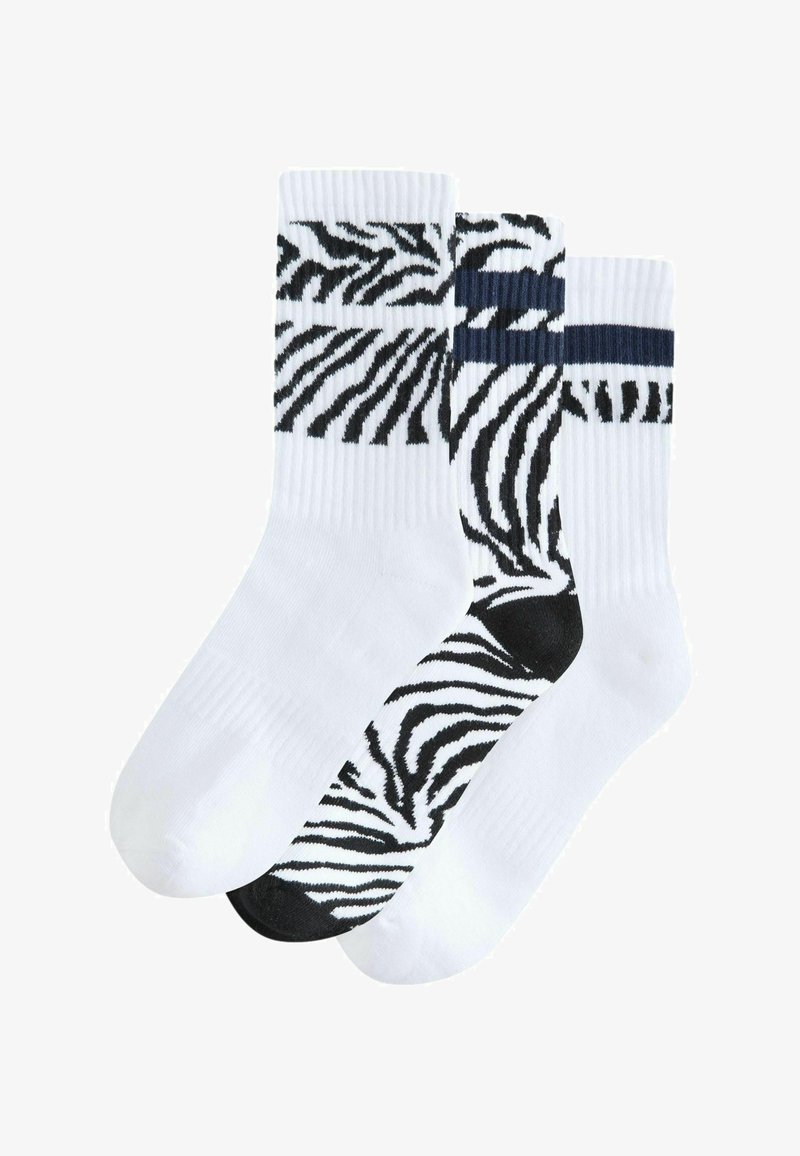 Drei Paar Baumwollsocken: zwei mit weißen und schwarzen Zebra-Streifen, eines einfarbig weiß mit dunkelblauen Akzenten am oberen Rand.